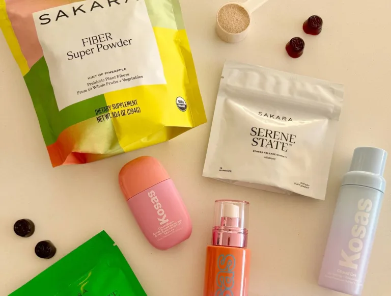 An image of several products laying across a table: Sakara Fiber Super Powder, Serene State, Metabolism Bite, Night Service, Beauty Biome, and then Kosas Sunscreen, Face Mist, and Collagen Serum