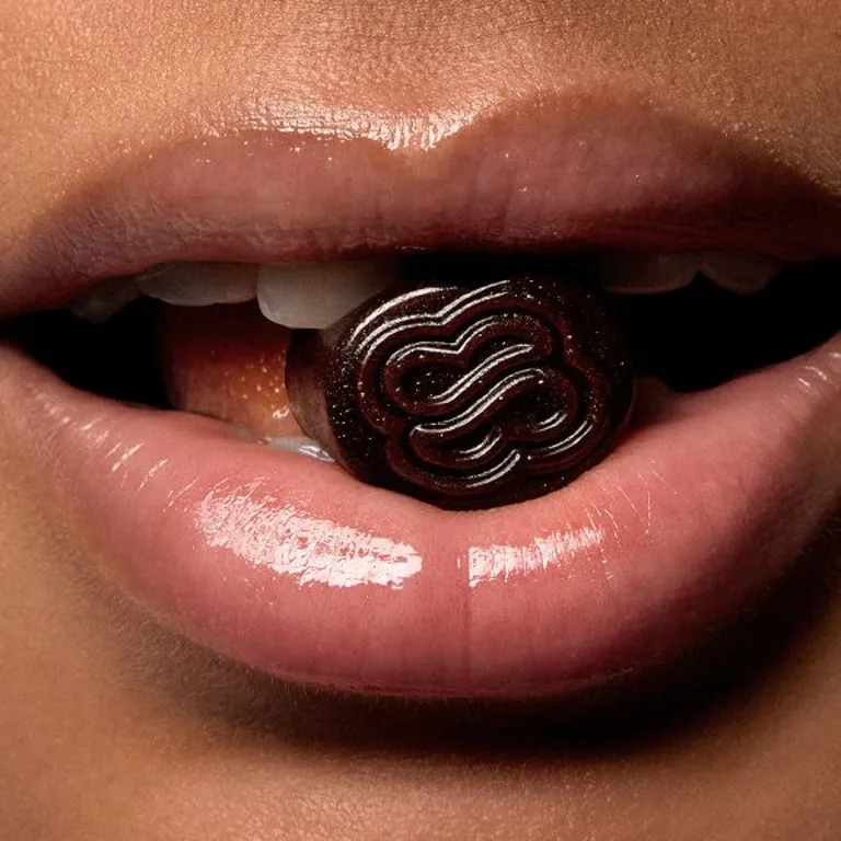 A close up of a female's face, biting into Sakara's Metabolism Bite gummy.