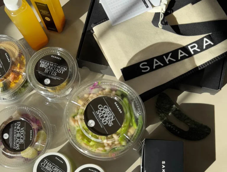 Sakara Level II: Detox meal containers including Core Greens Salad and Kale + Mushroom Breakfast Bites beside orange juice, a canvas Sakara tote bag, and packaged items.