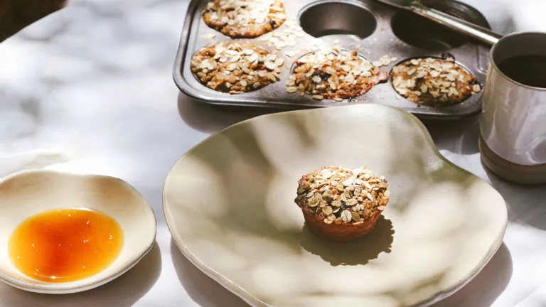 Baked muffins in a tin and a small dish of honey.