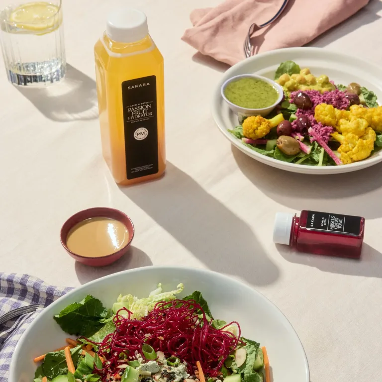Sakara level II: detox meals and passion fruit hydrator placed on a table with beige tablecloth.