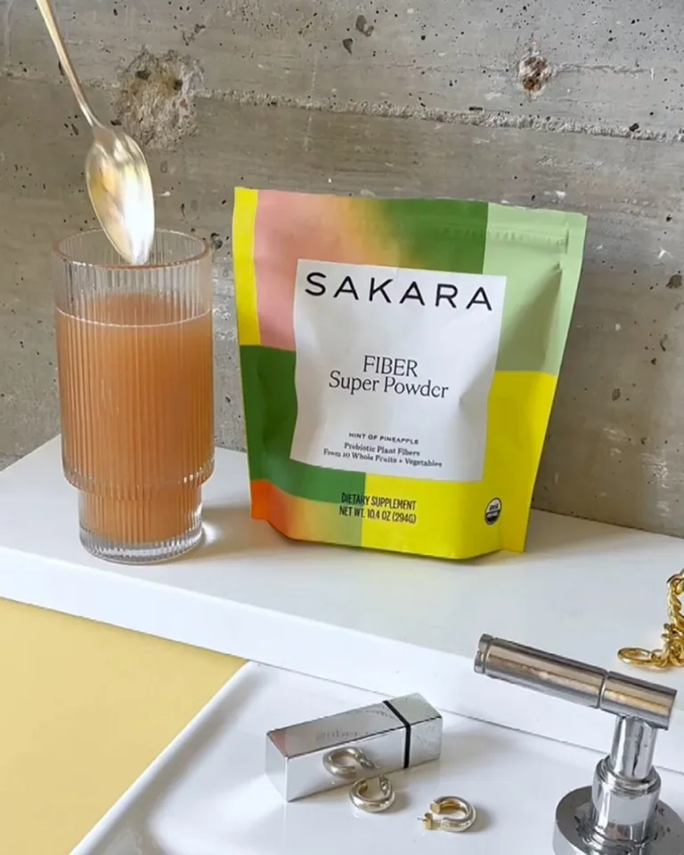 Sakara Fiber Super Powder on bathroom counter next to a glass of water with Fiber Super Powder mixed in