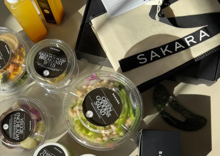 Sakara Level II: Detox meal containers including Core Greens Salad and Kale + Mushroom Breakfast Bites beside orange juice, a canvas Sakara tote bag, and packaged items.