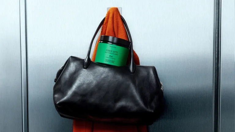 Banana balanced on stacked green apple slices with pears and figs on a white surface.