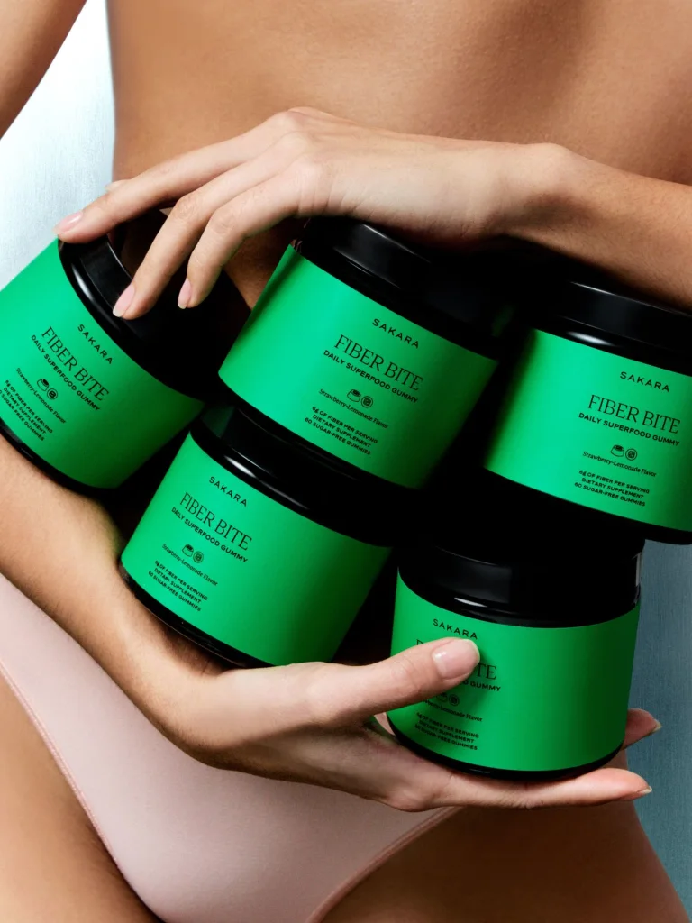 Female holding several containers of Sakara Fiber Bite