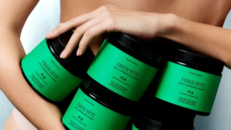 Female holding several containers of Sakara Fiber Bite