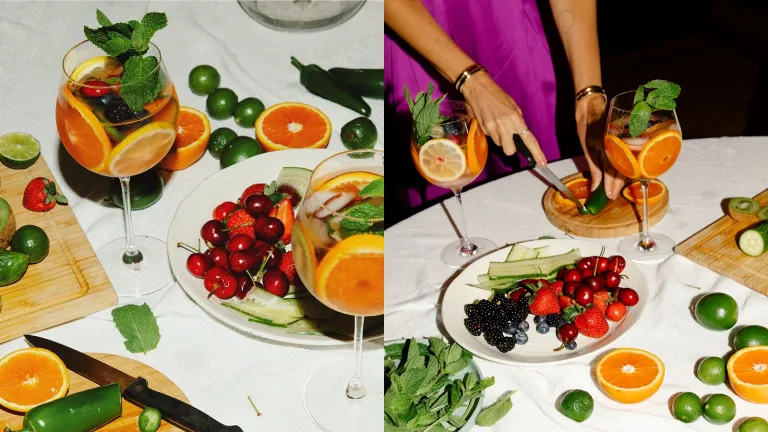 Split-image collage of a citrus spritz setup—left shows two garnished wine glasses filled with a fruit-forward drink surrounded by sliced oranges, limes, jalapeño, and fresh berries; right shows a woman in a pink satin outfit slicing jalapeño on a cutting board beside the prepared spritz glasses and a plate of mixed fruit on a white tablecloth.