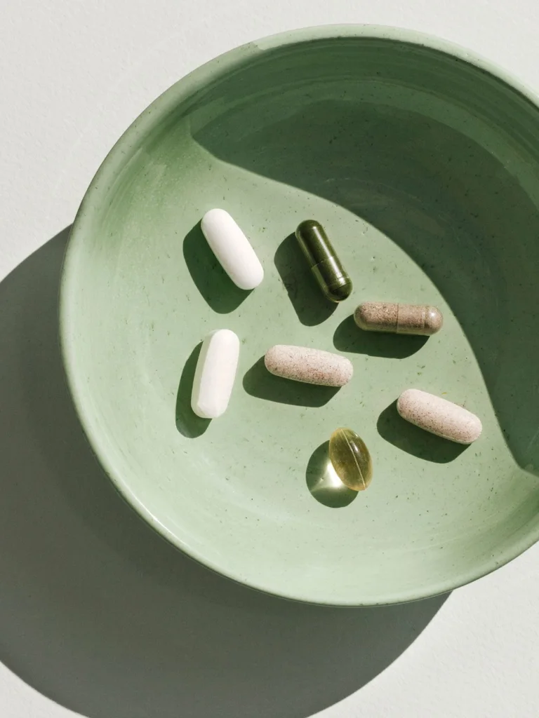6 prenatal pills in a green bowl with a large shadow in the background
