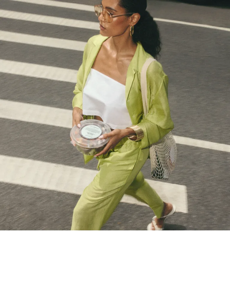 woman in green suit walking across the street 