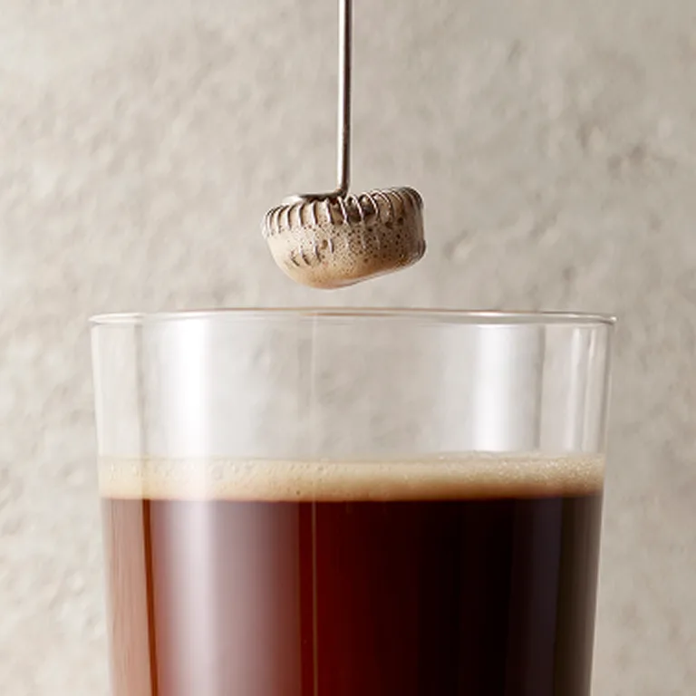 cup with metabolism super powder and water with a frother above 